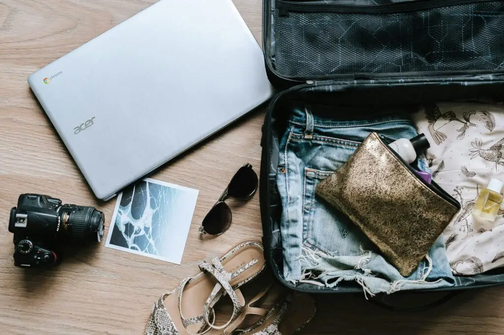 packing list for teaching abroad — laptop, camera, sandals, and essentials laid out next to open suitcase