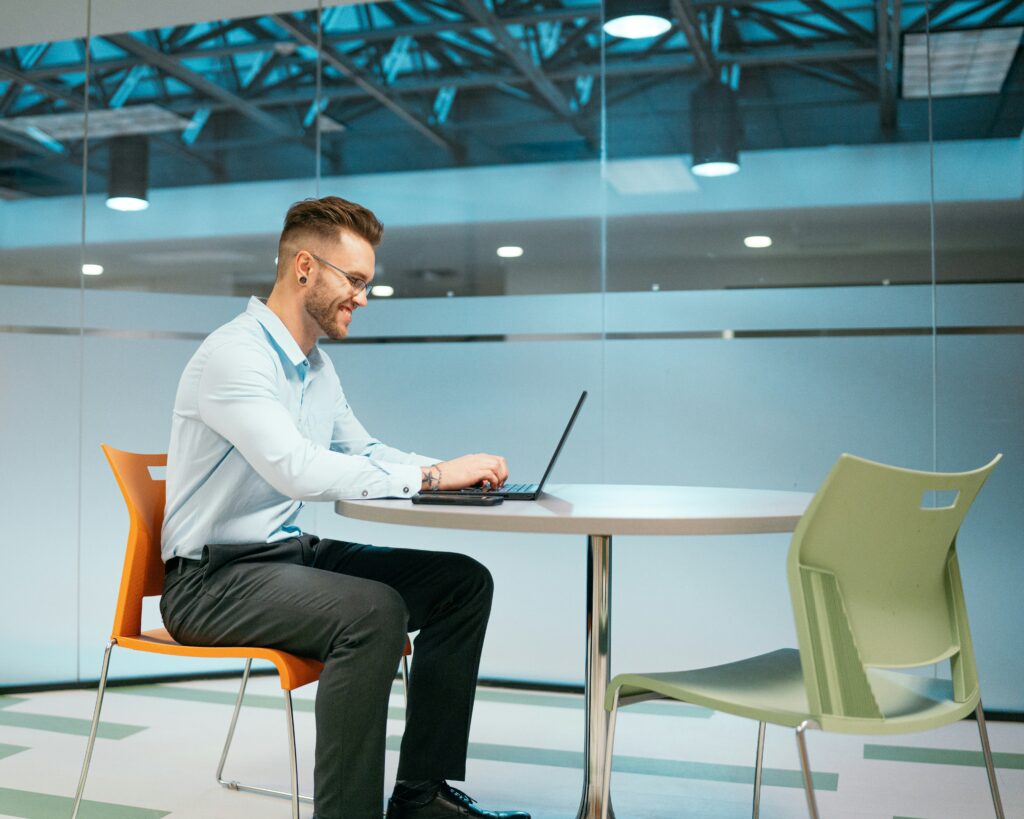 Man sitting alone at a modern table working on a laptop — representing the preparation and paperwork that what nobody tells you before you teach abroad says matters more than most people think