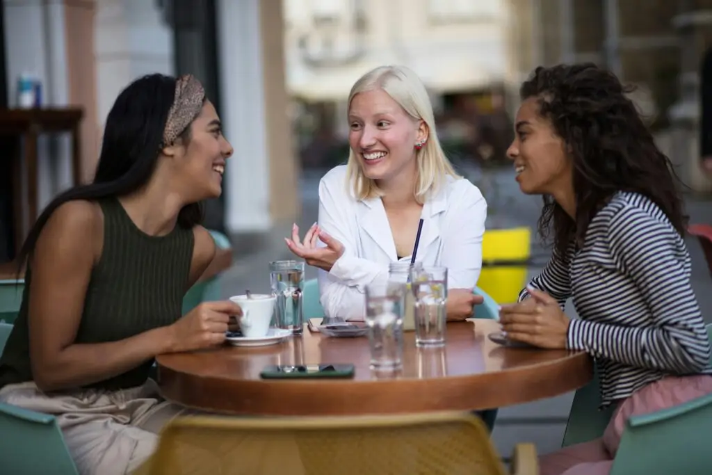 how to make friends living abroad — three women laughing at outdoor café table