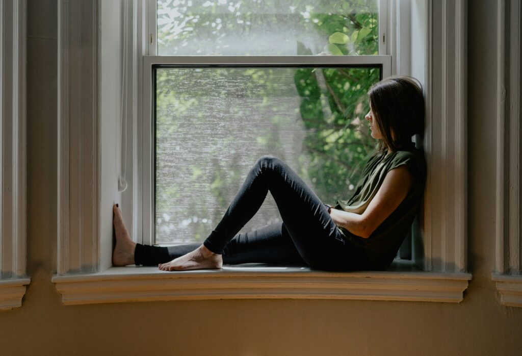 Woman sitting alone in a window seat experiencing reverse culture shock after returning from living abroad