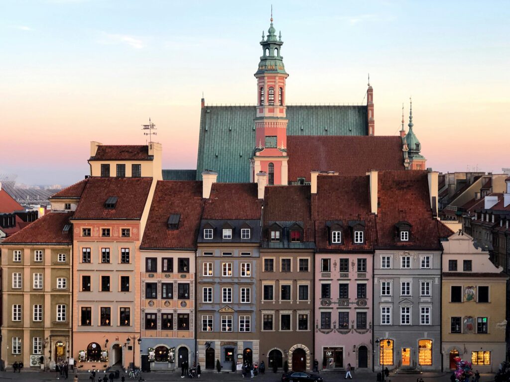 Warsaw's Old Town Market Square at sunset with colorful historic townhouses and the tower of St. John's Archcathedral — a highlight for teachers who teach English in Poland
