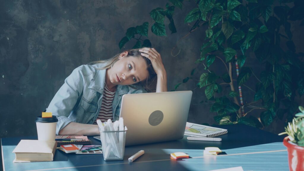 Exhausted burned out teacher at desk with laptop — teaching abroad can be the reset you need