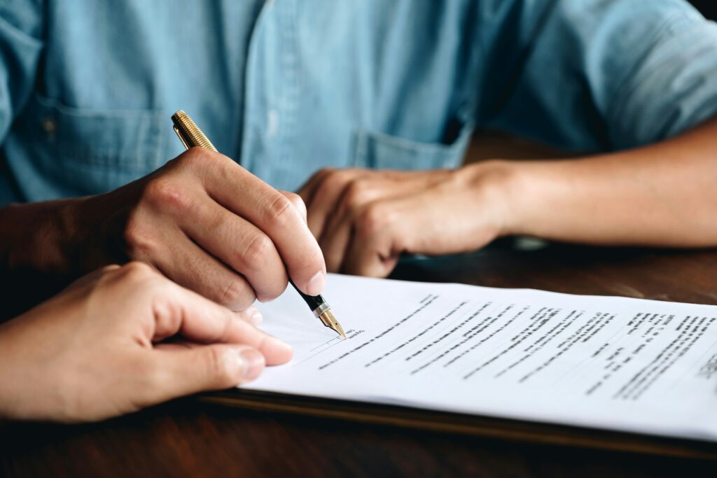 Person signing a contract with a fountain pen — read every line before you sign a teaching abroad contract