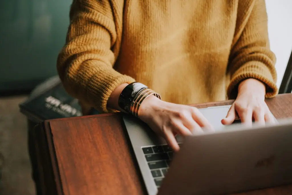 Person typing on a laptop while writing their international teaching CV