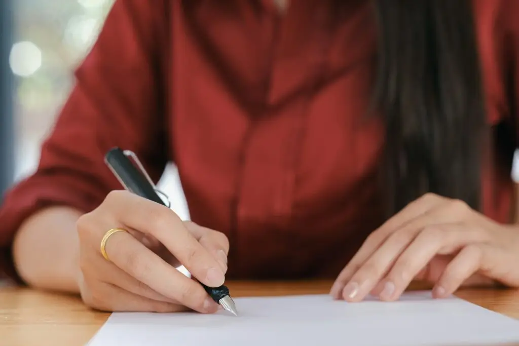 Close-up of a hand signing a Prague apartment lease with a fountain pen.