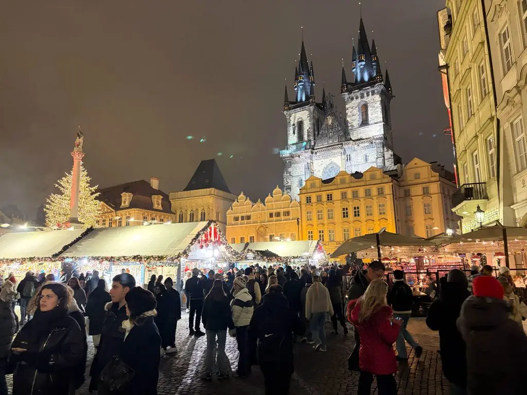 Prague Old Town Square Christmas market with Týn Church spires lit at night