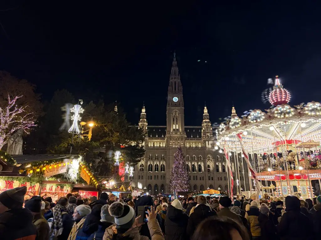 Vienna Rathausplatz Christmas market at night with City Hall and carousel