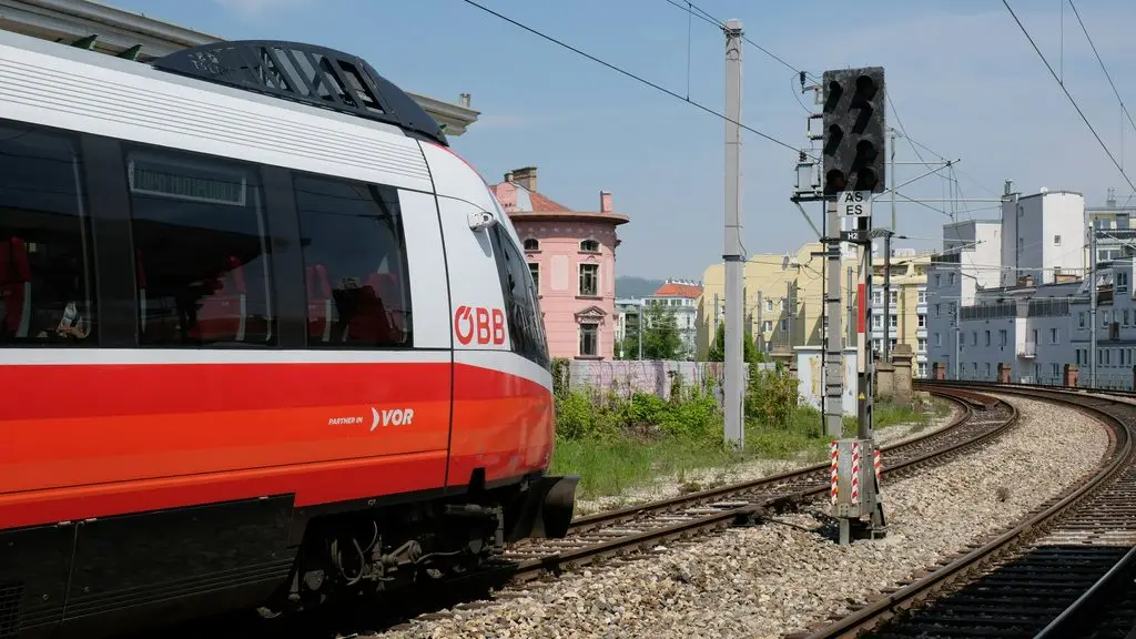 Vienna travel guide: red and white ÖBB train on the tracks in Austria, signal display reading Wien Flughafen.