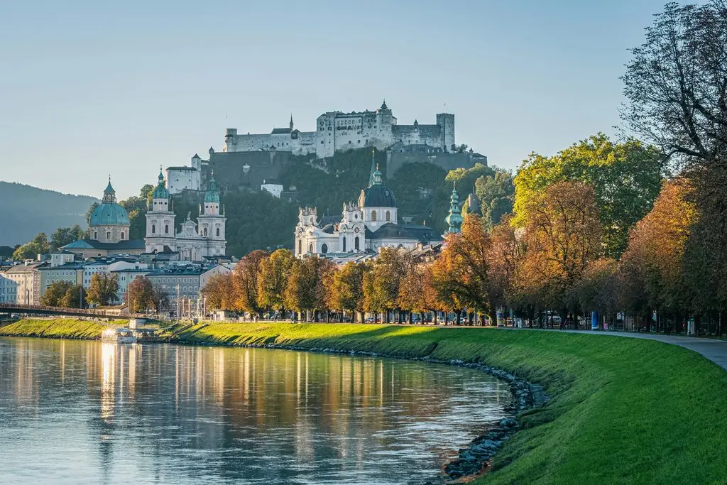 Vienna to Salzburg train trip: Hohensalzburg Fortress overlooks Salzburg's old town and the Salzach River in autumn.