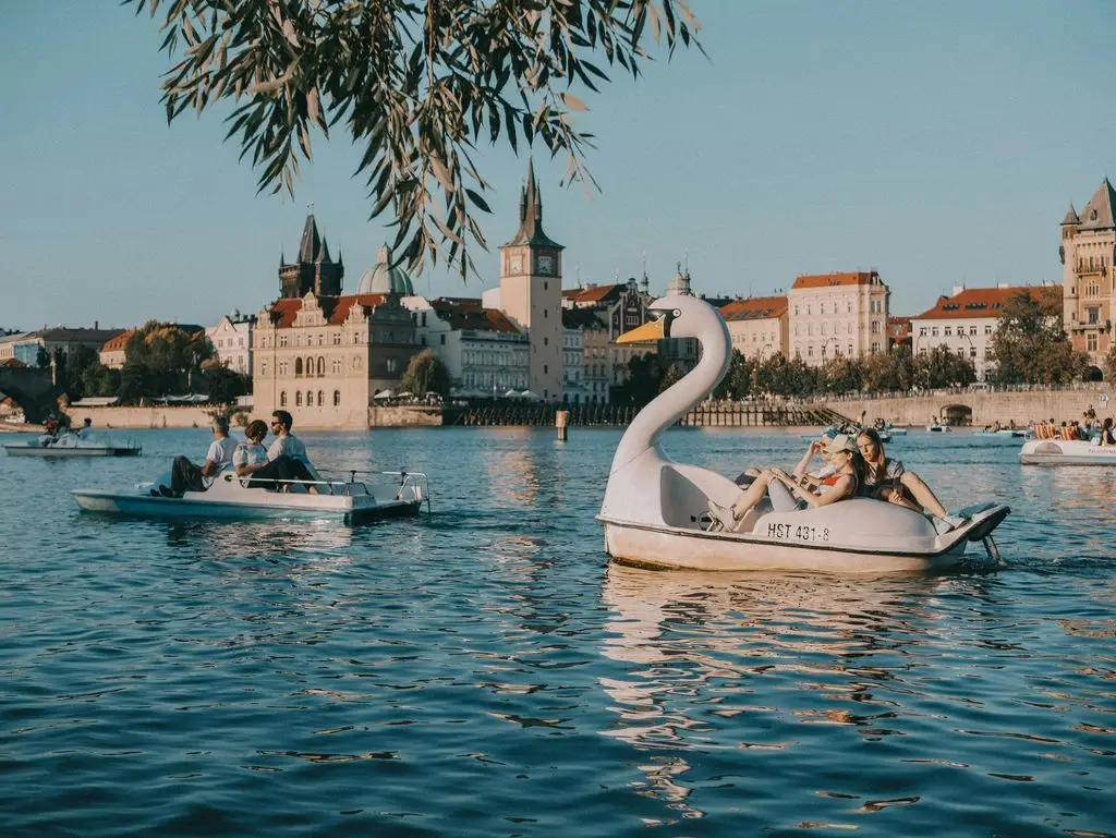 People on swan paddle boats on the Vltava River, teaching English in Prague this summer means time to enjoy it